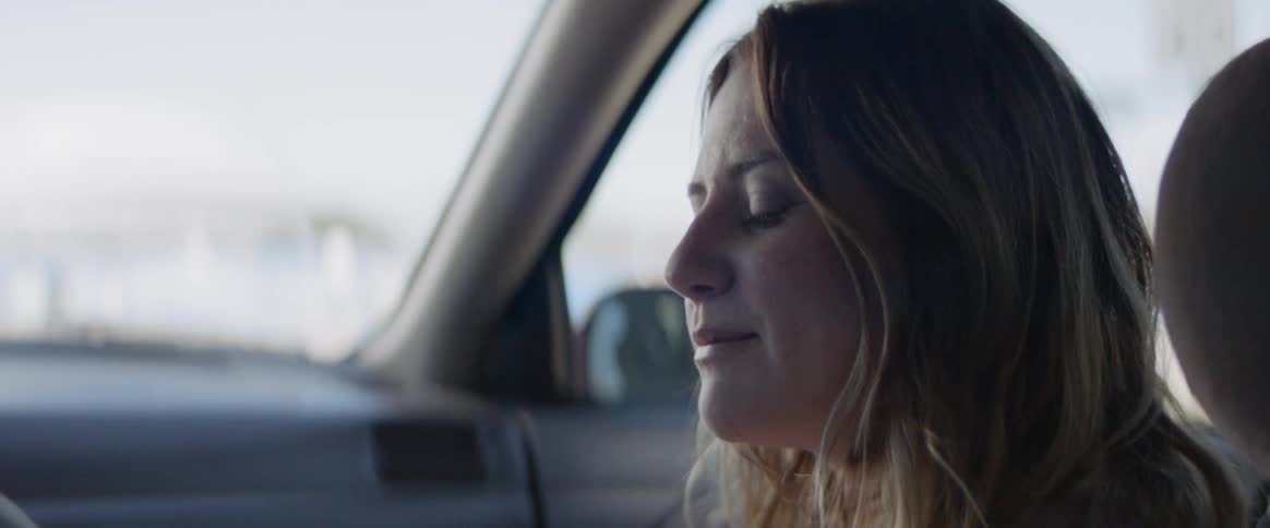 A woman nods her head in the passenger seat