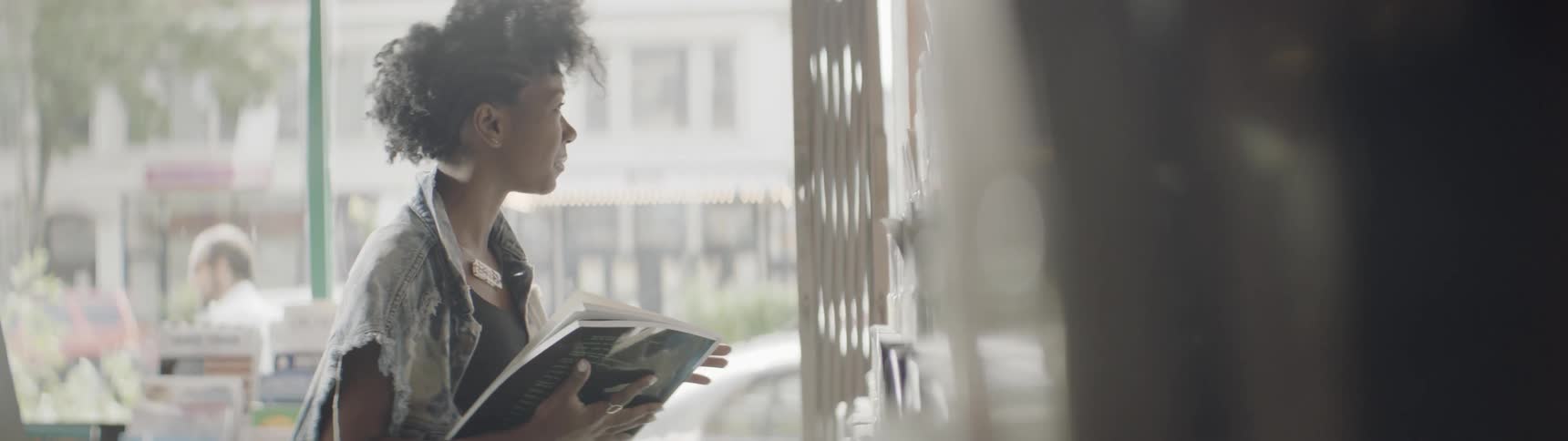 A woman looks at a magazine rack in a city