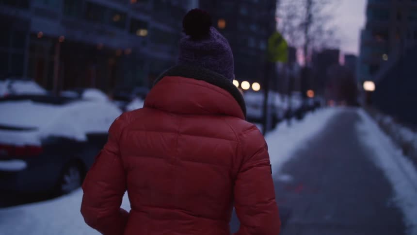 Woman walking down a sidewalk with snow on the side