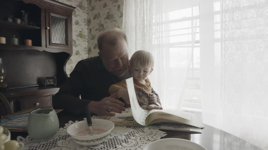 Man and toddler sit at table reading