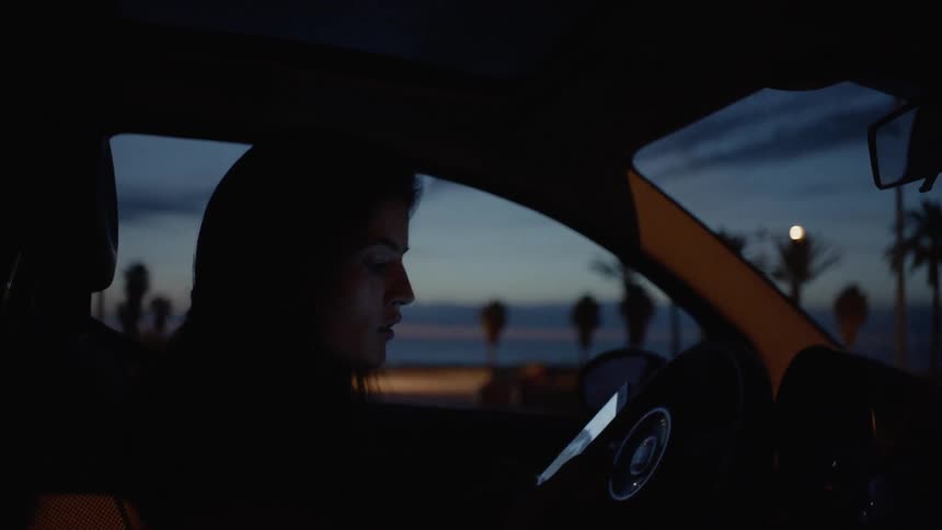 Man sits in a car looking at his phone at night