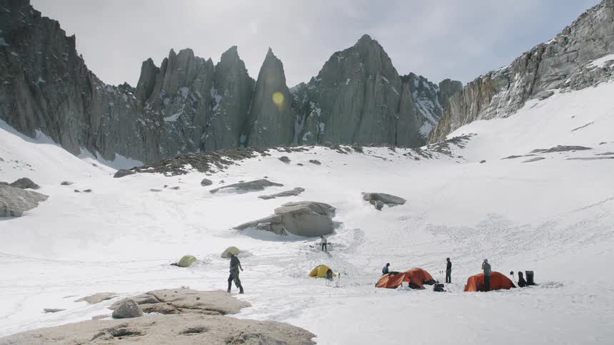 Group of people camp at the bottom of snowy mountains