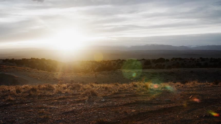 Sun rises over plains on a partly cloudy day