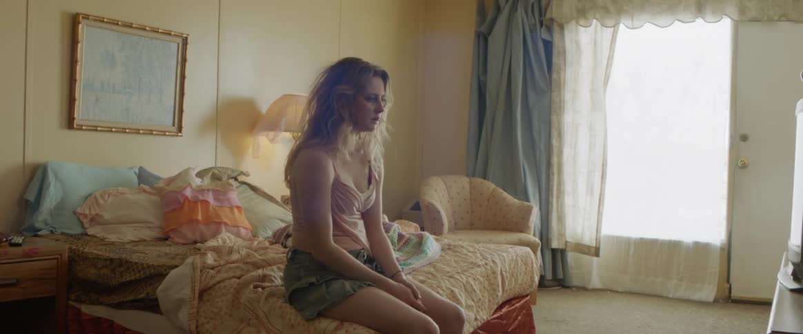 Sad looking woman sits on a bed