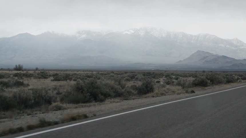 Road goes through a country field near mountains