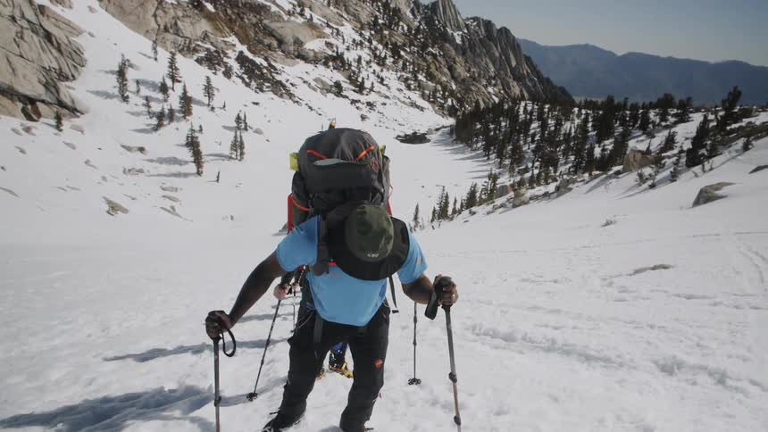 Climbers use ski poles to help them climb a snow covered slope