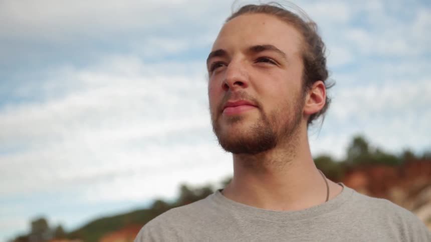 Man standing outside looks up and turns his head