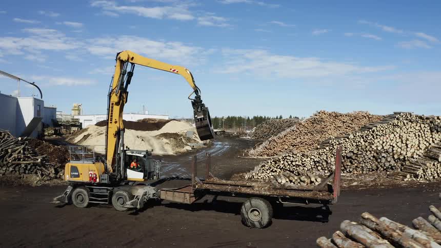 A logging vehicle works at a lumber yard