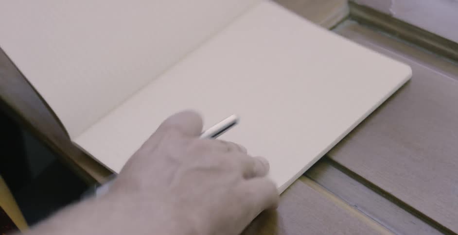 Person opens an empty journal while holding a pen