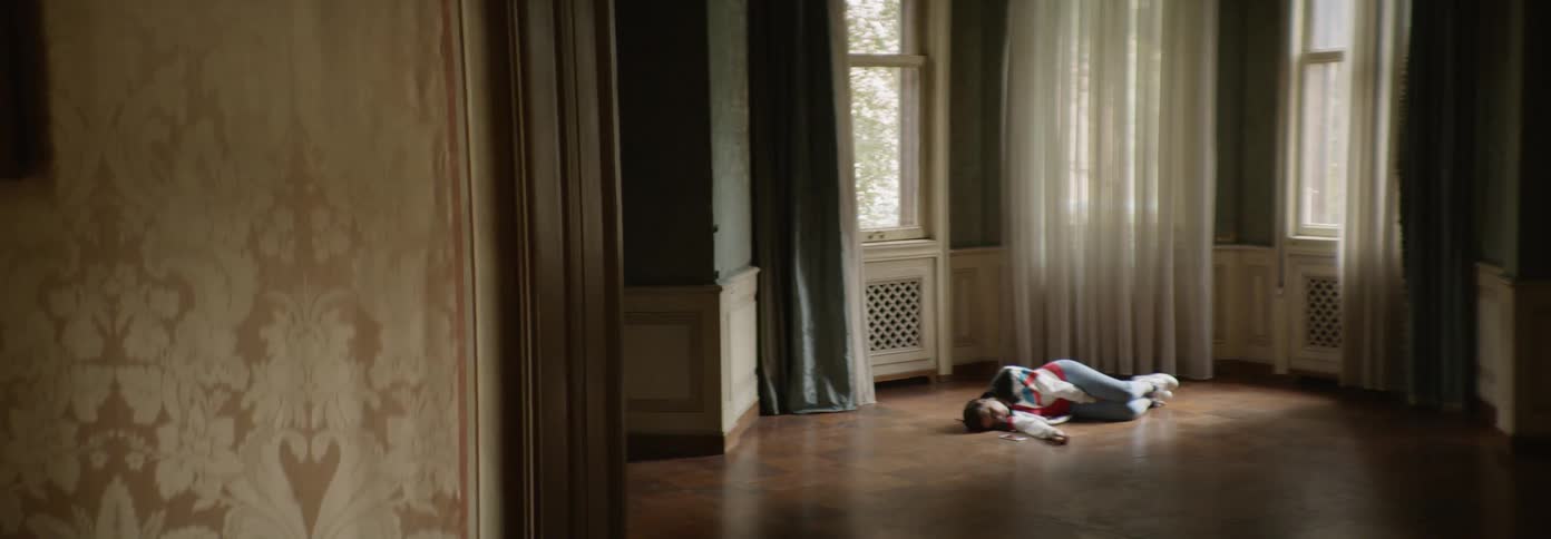 Woman laying on a floor in a room as if dead