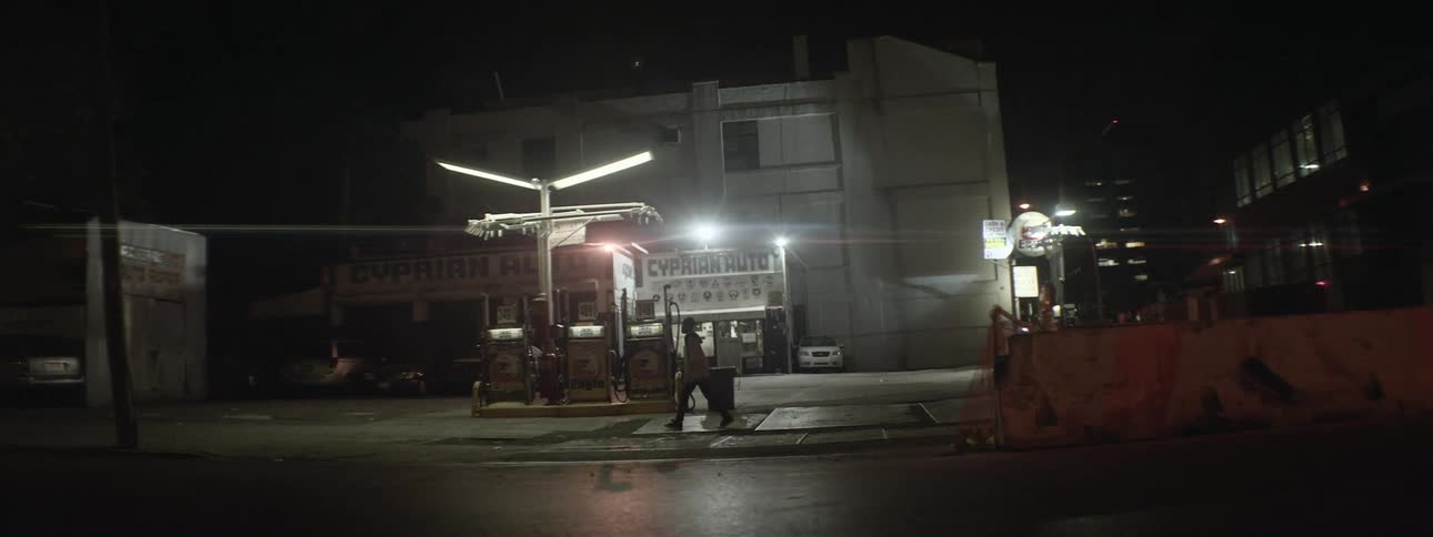 A man walking by an urban gas station at night