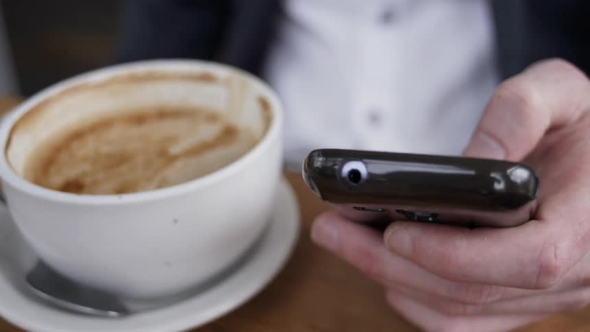 A man uses a phone inside a coffee shop