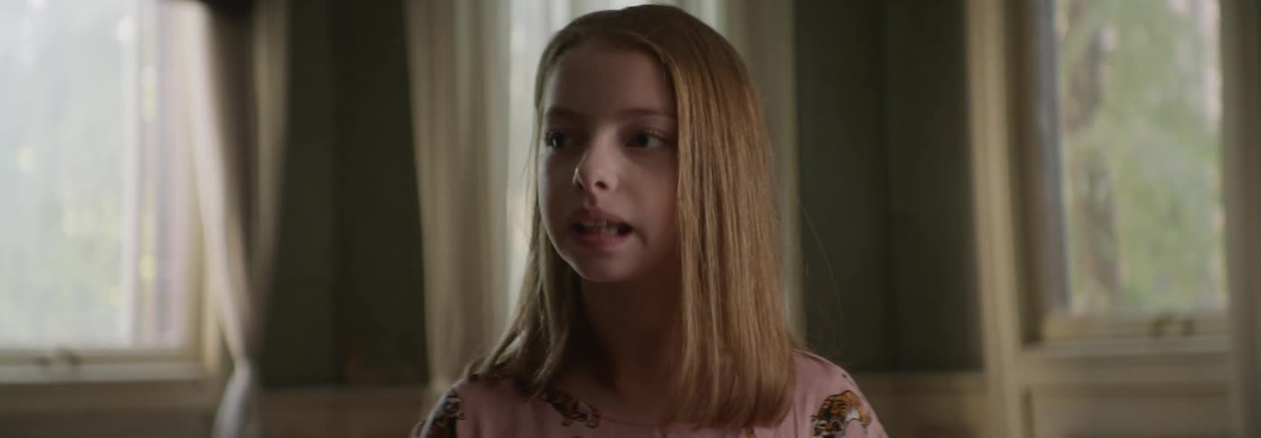 A girl standing in a room looks off to the side