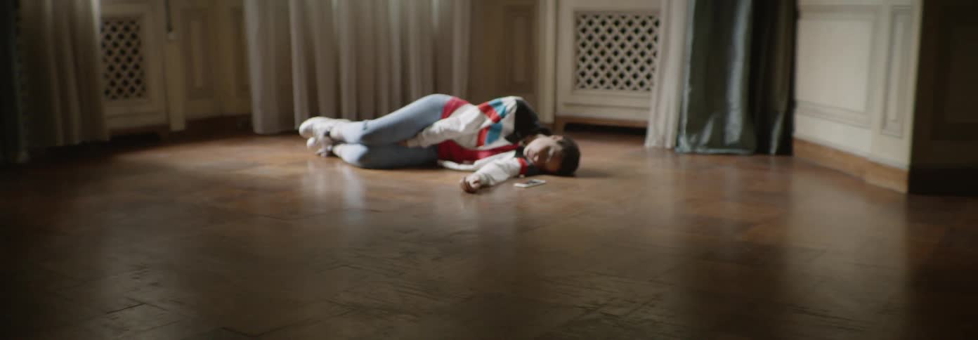 Woman lies on a wood floor next to a smartphone
