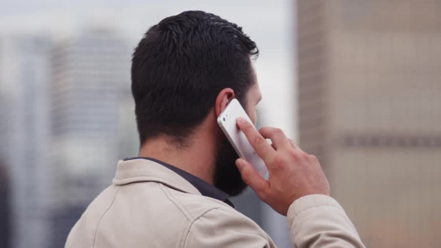 A man talks on a cellphone while standing outside in a city