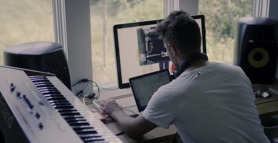 A man works on his computer near a keyboard