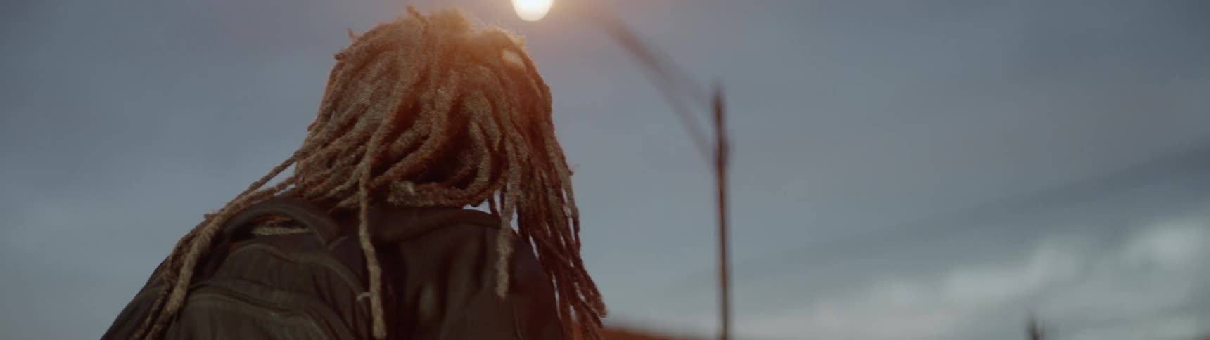 Man stands beneath a street lamp at dusk