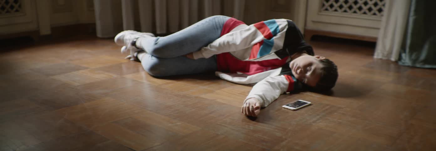 Young woman lays on the floor sleeping with a cell phone next to him