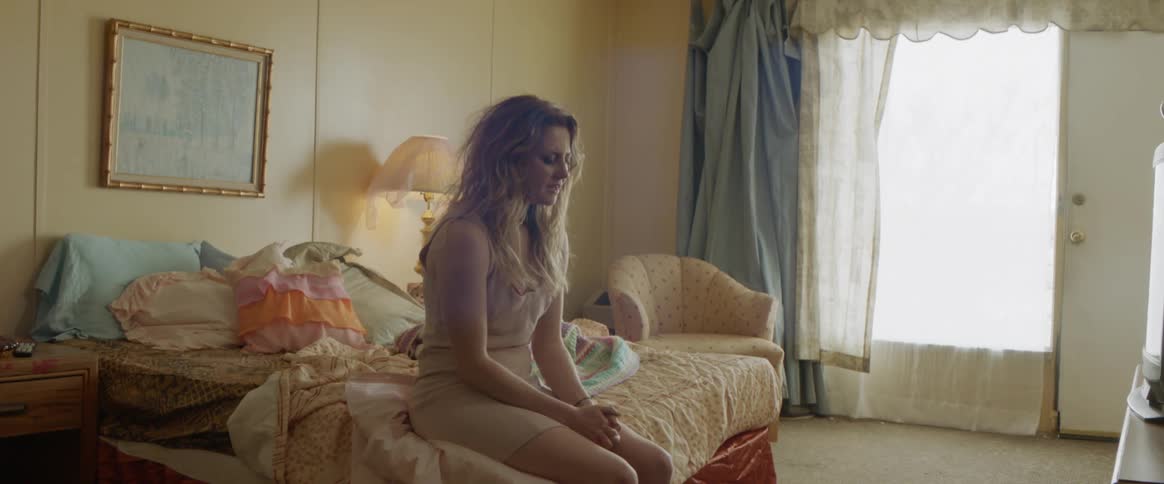 Woman sits at the edge of a bed crying