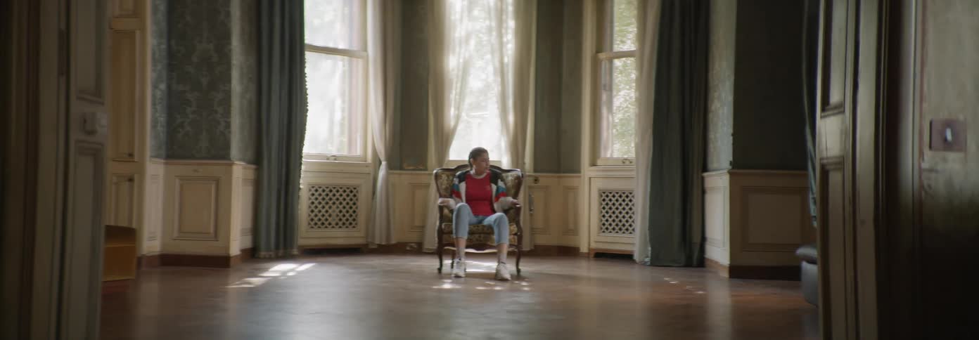 A woman sits in a chair in an empty room