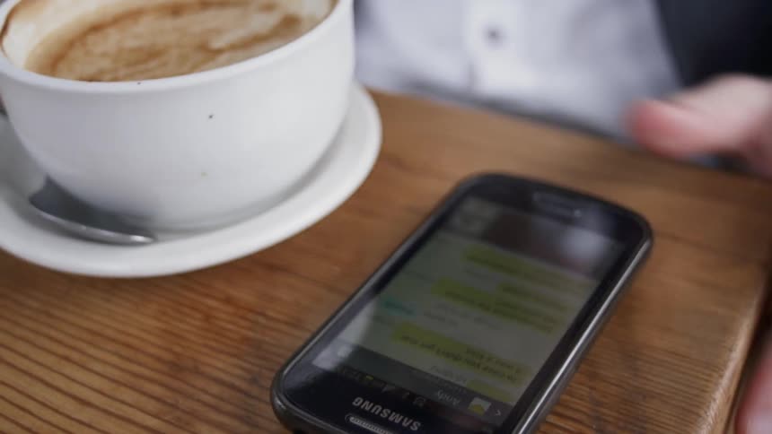 Man in cafe typing on phone