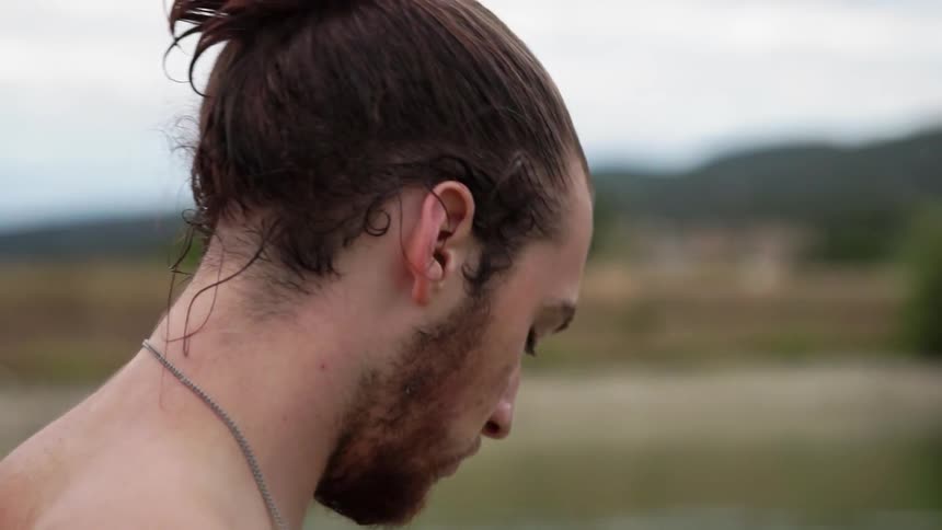 Shirtless man looks down then looks back up