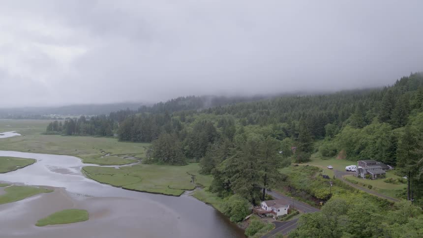 Clouds are hanging over homes in foothills near a river in daylight