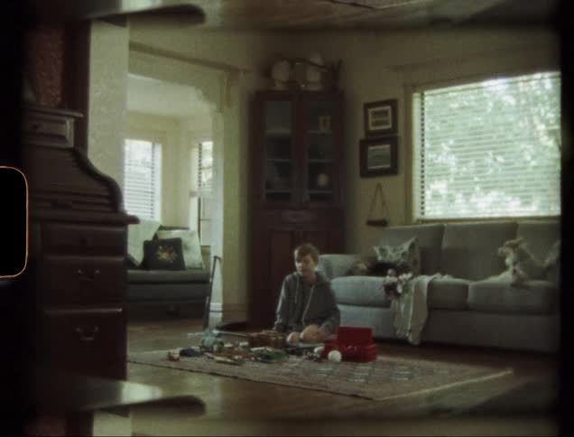 Boy is playing with toys on living room floor while dog lays on couch