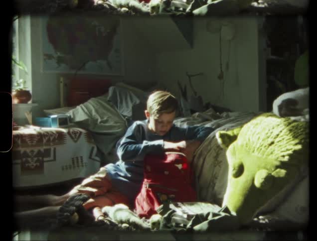 Boy empties a backpack on his bedroom floor