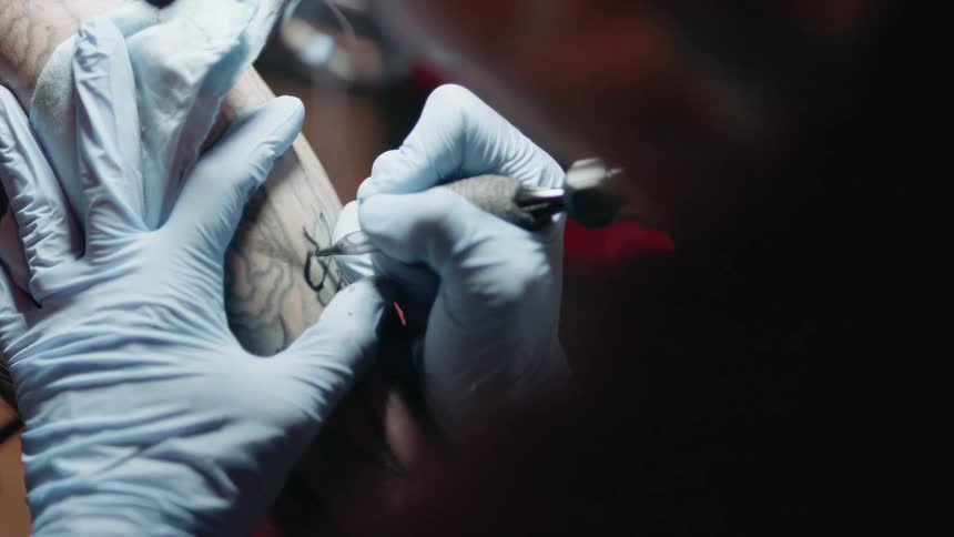 Person draws a tattoo on another person's arm