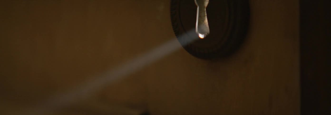 Light shines through the keyhole in a door