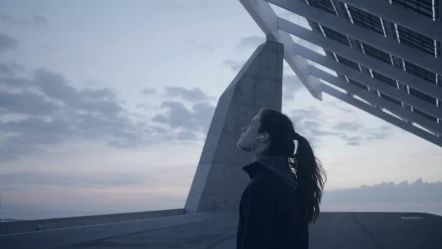 Woman standing near a stone structure at sunset