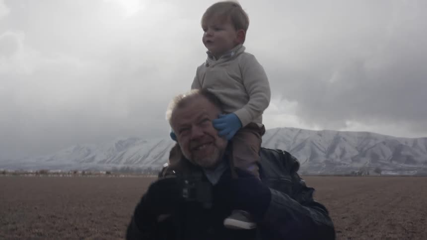 Man walks on mountain valley floor holding child