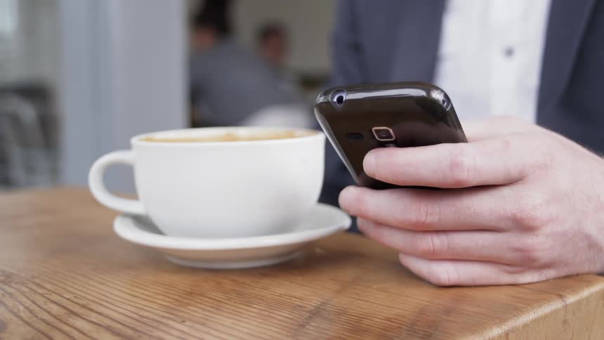 Women touches a cellphone that she is holding in her hand