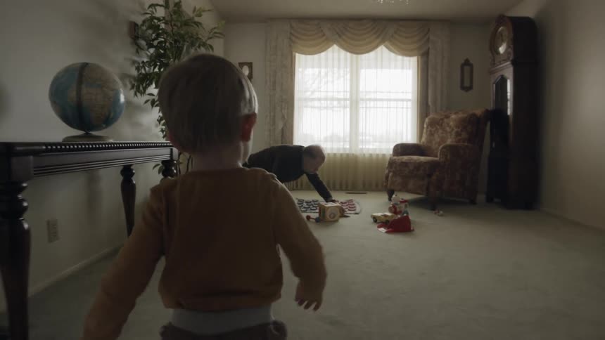 A boy enters a room where his grandpa is already playing with toys