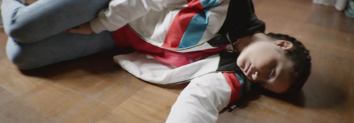 A girl is lying on a floor next to a cell phone in daylight