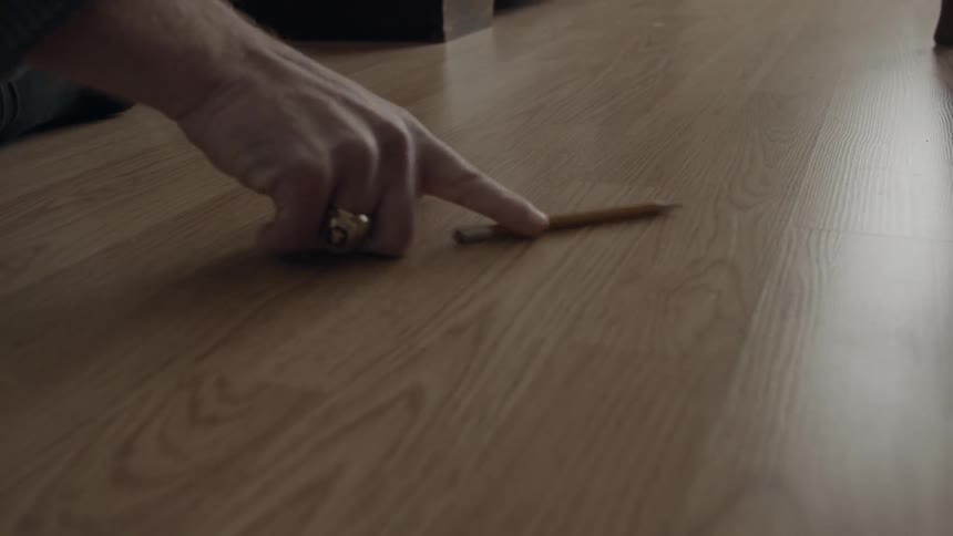 Person is rolling pencil on floor