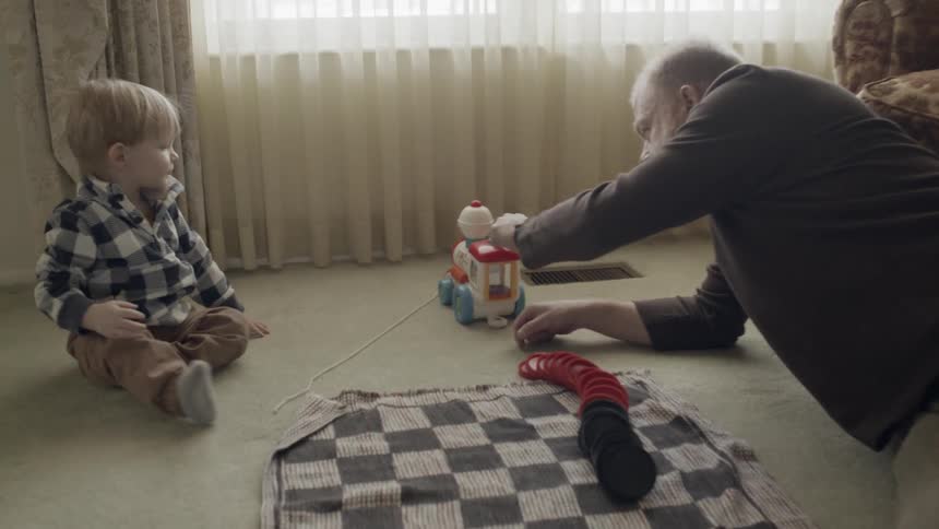 A man plays with a young child on the floor
