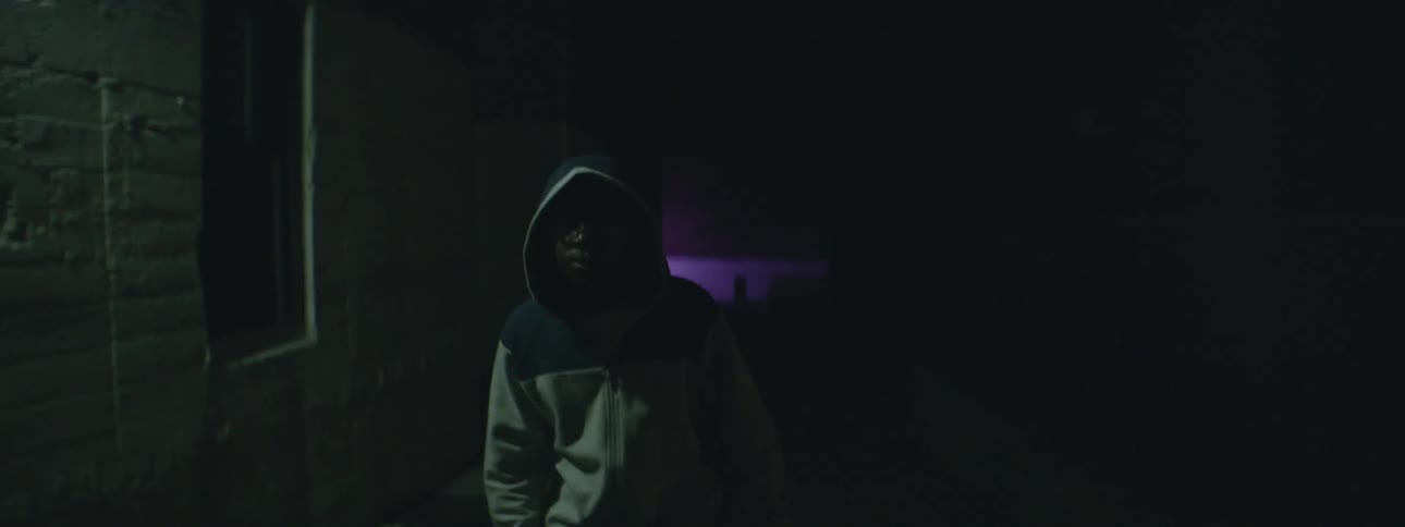 Hooded boy walks down a dark alley