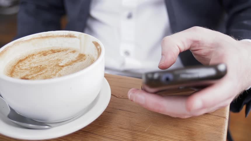 A man uses his phone at a coffee shop