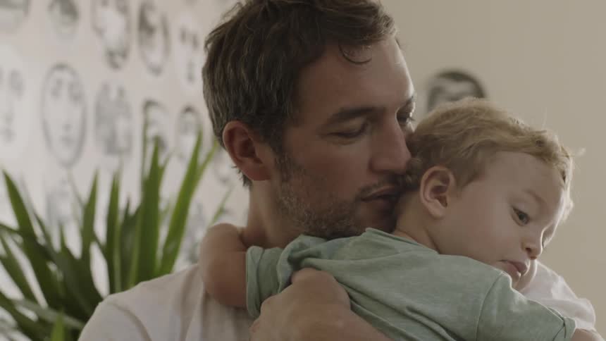 A father holds and kisses his young son