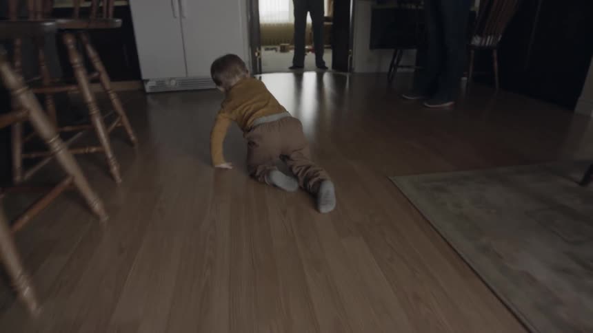 Toddler crawls across wooden floor
