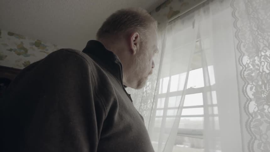 Man looks out a window at home
