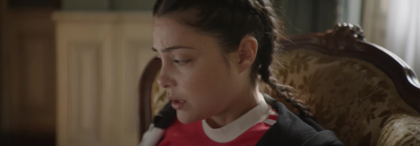 Woman sits in a chair looking anxious then gets up