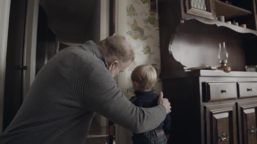 A man tries to mark a young child's height on the wall