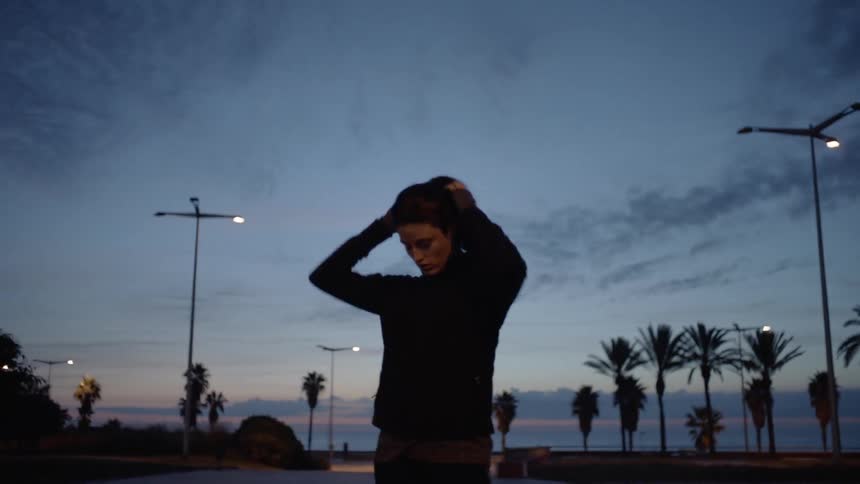 A woman ties her hair up outside