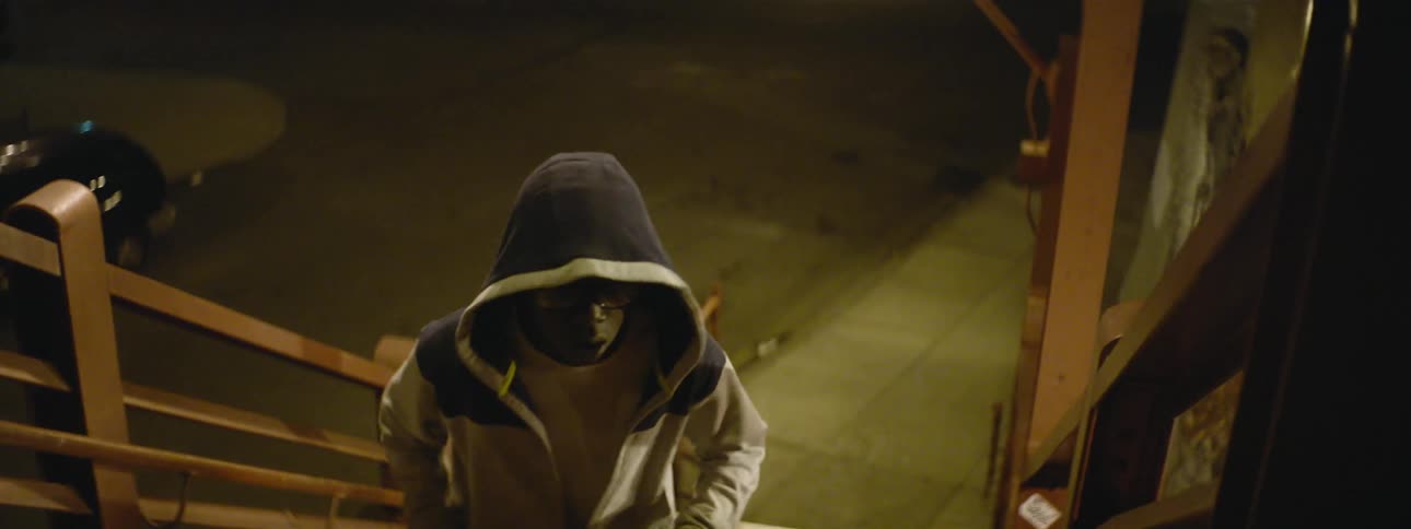 Young hooded boy ascends a staircase at night