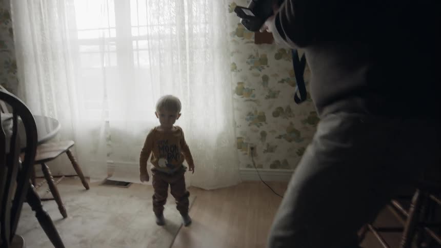 A man films a young child with a home camera