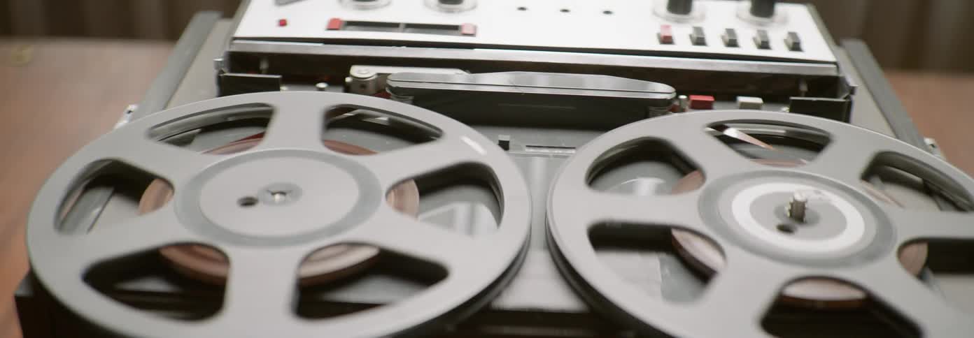 Tape deck reels are spinning as it plays inside in daylight