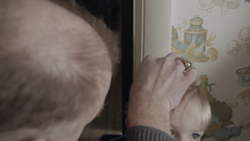 A man marks a child's height on the wall